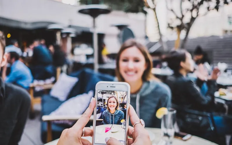 A phone filming a woman laughing at a café table
